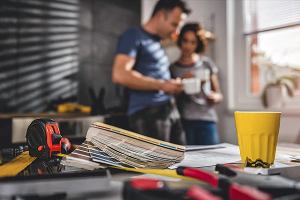 Foto de um casal um uma sala com uma mesa cheia de ferramentas.